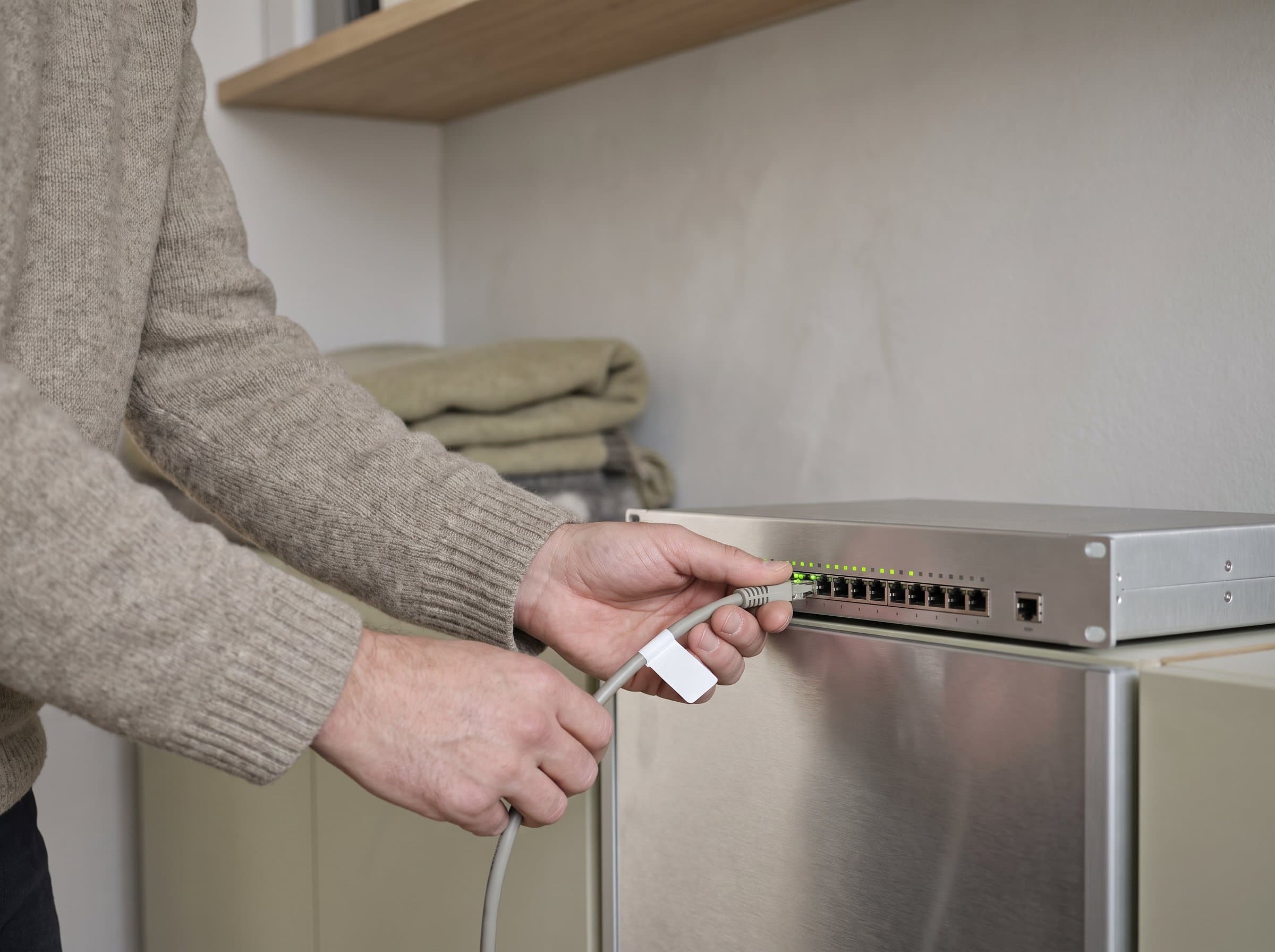 Ein Patchkabel wird in den Switch gesteckt, die Ports leuchten in einer Reihe
